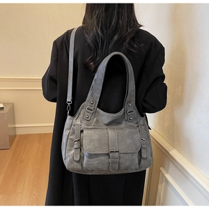 Close-up of retro grey tote bag with buckle flap pocket worn on shoulder by model