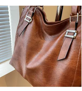 Detail of brown PU leather tote bag showing textured grain and silver metal buckle