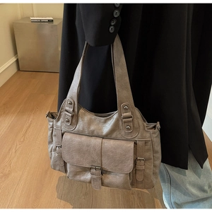 Detailed close-up of brown vintage leather handbag with buckle pockets and worn-out finish