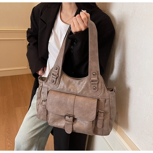 Detail of vintage soft leather tote bag showing belt buckle pocket and textured grain