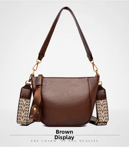 Detail of brown leather bucket bag featuring a vintage geometric woven wide strap