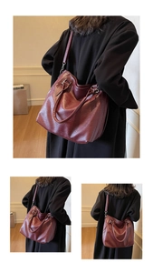 Detail view of burgundy pebble leather tote bag with dual handles and shoulder strap