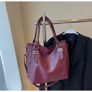 Detail of burgundy tote bag showing litchi grain texture and silver metal hardware