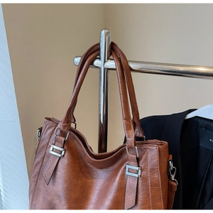 Detail of soft dark brown faux leather tote with vintage texture and metal hardware