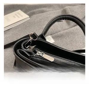 Gros plan d'un sac à main en cuir noir avec fermeture éclair et détails de clous argentés