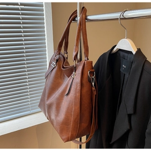Detail of brown leather tote bag with silver hardware and detachable shoulder strap
