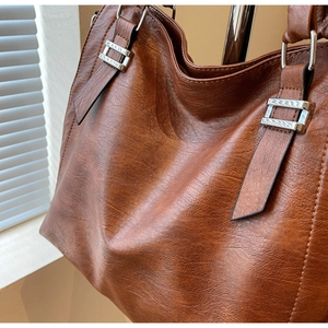 Detail of vintage brown tote bag showing pleated leather texture and silver buckle