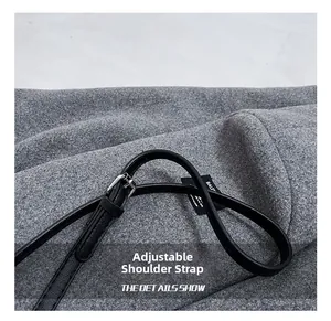 Détail d'une bandoulière réglable en cuir noir grainé avec une boucle argentée