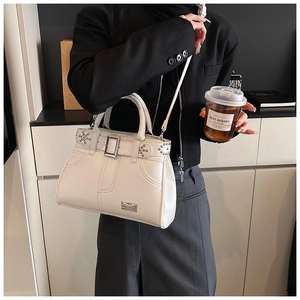 Détail du sac à main en cuir blanc crème avec rivets et sangle de ceinture décorative