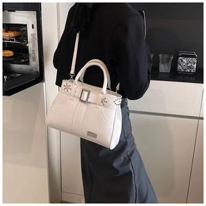 Sac à main chic en cuir blanc avec boucle en métal et rivets porté en bandoulière