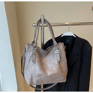 Detail of taupe pebbled leather tote bag with metallic buckles and crossbody strap