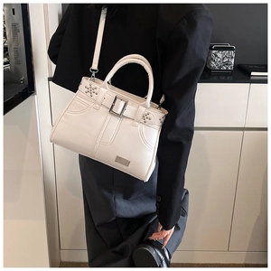 Gros plan du sac seau blanc avec rivets et bandoulière, porté par un mannequin en blazer