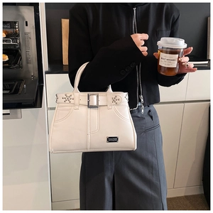 Détails d'un sac à main blanc en cuir clouté avec boucles métalliques et rivets argentés