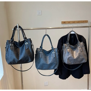 Detailed view of large PU leather tote bags in black, blue, and grey with silver buckles