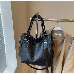 Detail of black pebbled leather tote bag with silver hardware and adjustable strap