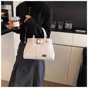 Détail du sac à main blanc clouté avec motif ceinture et plaque métallique