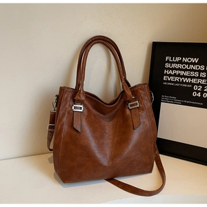 Detail of a brown tote bag with pebble leather texture, silver hardware and a shoulder strap