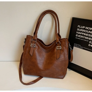 Close-up of brown litchi grain leather tote bag with metallic rings and handle detail