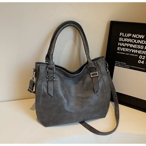 Detail of dark grey tote bag with lychee pattern faux leather and silver metal buckles