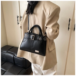 Détail d'un sac à main noir à rivets avec boucle argentée et bandoulière sur mannequin