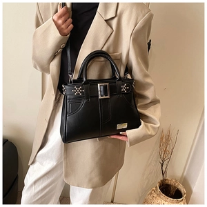 Détail du sac en cuir mat noir avec clous étoiles argentés et boucle carrée métallique