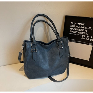 Close-up of pebble-textured leather tote bag with dual handles and silver hardware