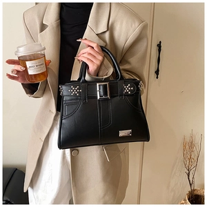 Détail du sac à main noir riveté avec boucle argentée et texture cuir mat