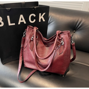 Close-up of wine red tote bag with pleated lychee texture and silver hardware details