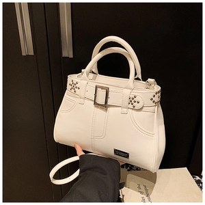 Détail du sac à main crème avec rivets, boucles de ceinture et plaque de marque en métal
