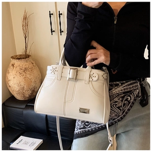 Détail du sac à main blanc cassé avec rivets argentés et texture en cuir élégante