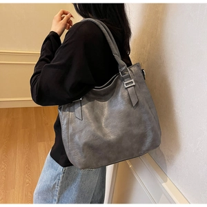 Detailed side view of a large grey vintage leather tote bag shown on a female model
