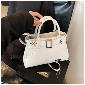 Détail d'un sac cabas en cuir blanc avec rivets argentés posé sur un blazer noir