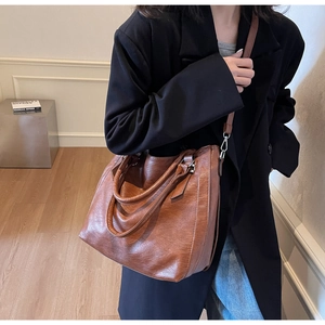 Detail view of brown leather tote bag with silver hardware and adjustable shoulder strap