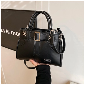 Détail du sac à main en cuir mat noir avec ceinture à boucle métal et clous argentés