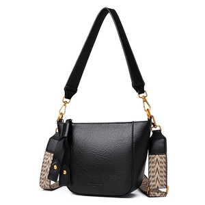 Black leather bucket bag with wide ethnic strap and gold hardware on white background