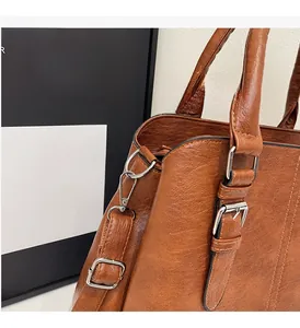Detail of vintage brown lychee grain leather handbag with silver metallic buckle and D-ring