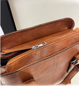 Close-up of smooth silver metal zipper and brown leather texture on handbag