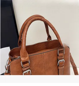 Detail of the reinforced dual handles with silver buckles on a brown leather handbag