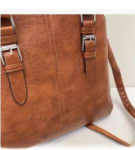 Detailed close-up of brown pebbled leather texture with silver buckles and dual stitching