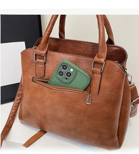 Close-up of the front zipper pocket on a brown tote bag showing smartphone storage