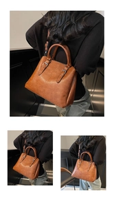 Detail of vintage brown leather tote bag showing double handles and buckle belt decoration