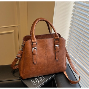 Close-up of brown textured faux leather tote bag with silver buckles and adjustable strap