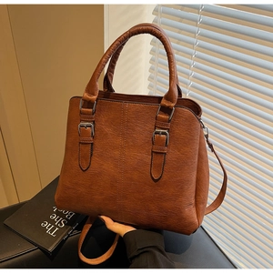 Close-up of dark brown lychee pattern leather handbag with silver metal buckle details