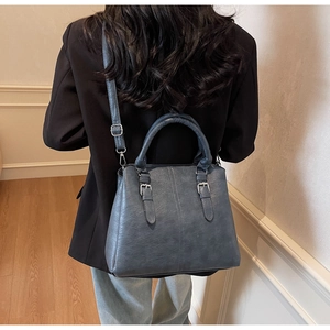 Rear view of a model wearing a greyish-blue vintage leather shoulder bag for daily commuting