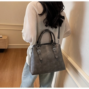 Detail of dark grey retro tote bag with dual straps and metallic buckle accents