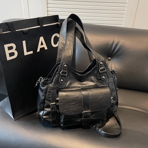 Retro black large tote bag with oily leather texture and multi-pocket design on sofa