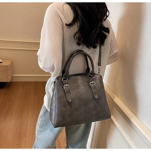 Rear view of model holding large dark grey lychee pattern tote bag for daily commute