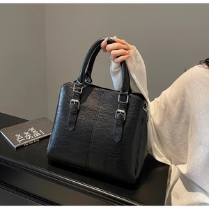 Detail of black lychee grain tote bag showing silver buckle and premium texture