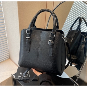 Detail view of black lychee texture leather bag with silver buckles and mirror reflection