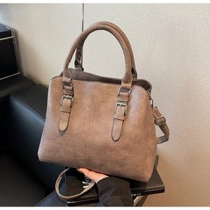 Detail of a vintage tan leather tote bag with elegant metal buckles and top handles